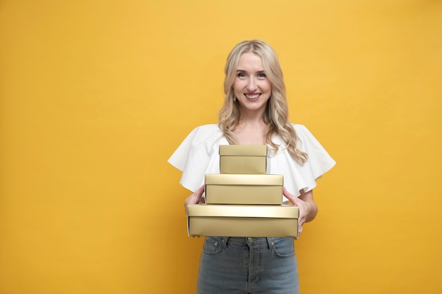 Feliz mujer europea rubia en blusa blanca con un paquete de caja de regalo