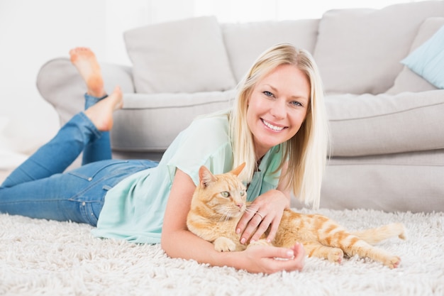 Feliz mujer con gato acostado en la alfombra