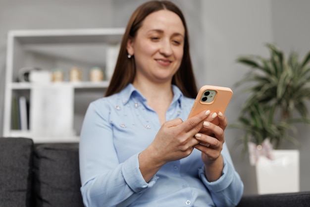 Feliz mujer hermosa casual hablando por teléfono mientras se sienta en el sofá en casa mujer joven sonriente