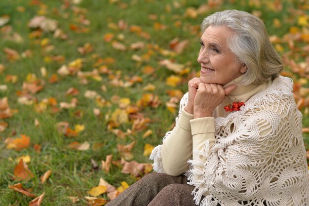 feliz mujer hermosa senior con bayas en el parque otoñal