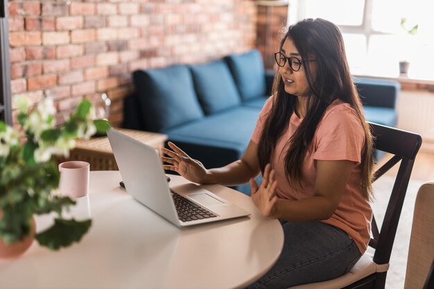 Feliz mujer india independiente o empresaria tiene videoconferencia hablando trabajando de forma remota en línea en la oficina en casa copia espacio videollamada y concepto de diversidad