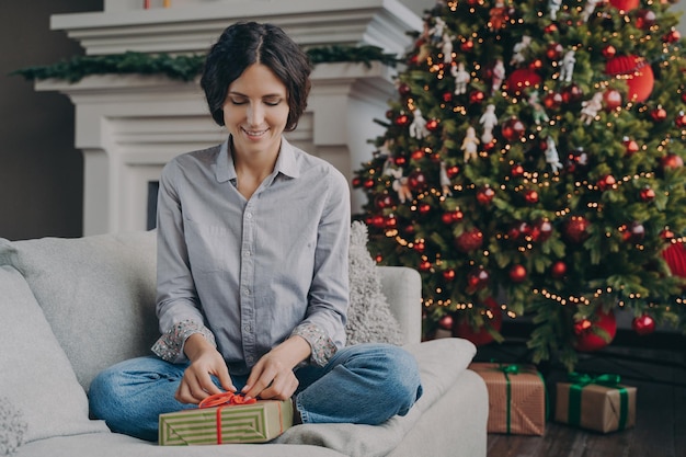 Feliz mujer italiana preparándose para navidad en casa envolviendo y empacando regalos de navidad