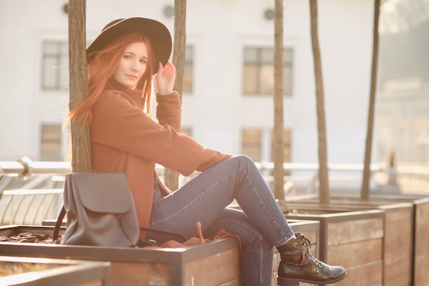 Feliz mujer de jengibre fabulosa en elegante sombrero en la calle