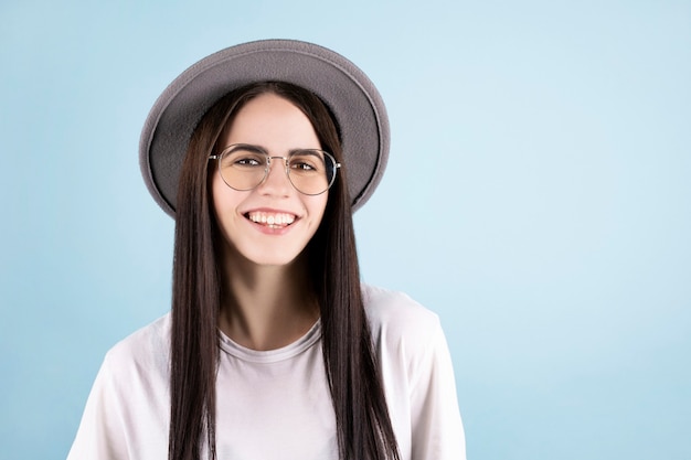 Feliz mujer joven alegre con su sombrero gris mirando a la cámara con una sonrisa alegre y encantadora.