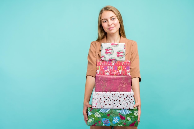 Feliz mujer joven y bonita con caja de regalo sobre fondo azul.