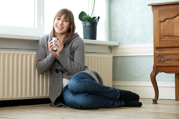 Foto feliz mujer joven relajante en casa con una taza de té