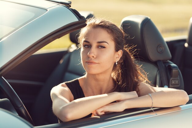 Feliz mujer joven sentada en su coche