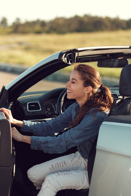 Feliz mujer joven sentada en su coche