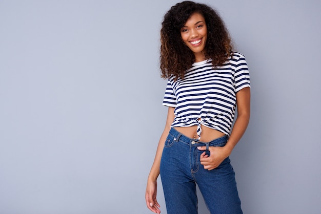 Feliz mujer joven sonriendo en camisa a rayas sobre fondo gris