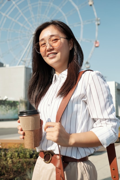 Feliz mujer joven con un vaso de café disfrutando de un descanso