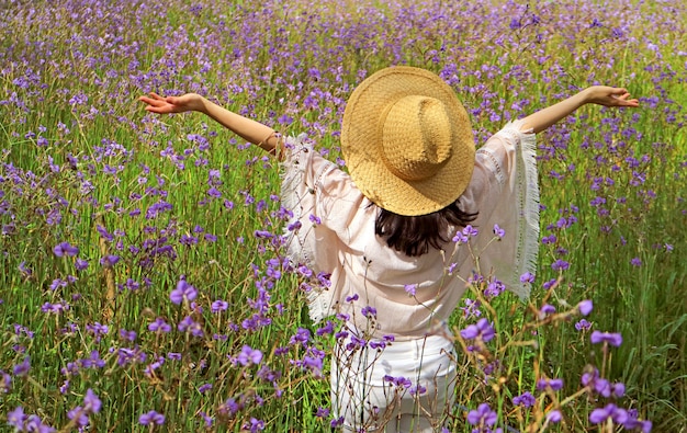 Feliz mujer levantando los brazos disfruta de la luz del sol en el hermoso campo de flores de color púrpura