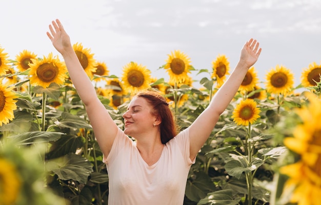 Feliz mujer libre abrió los brazos caminando en el floreciente campo de girasol El concepto de libertad Mujer joven mano sobre fondo de naturaleza