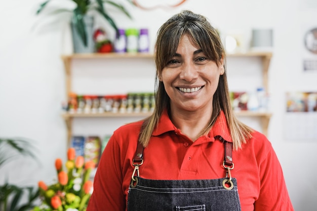 Foto feliz mujer madura latina trabajando dentro del supermercado mientras sonríe a la cámara