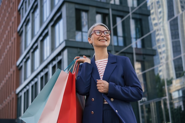 Feliz mujer madura sosteniendo bolsas de la compra.