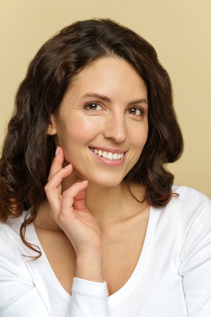 Feliz mujer milenaria con maquillaje natural, piel limpia perfecta y sonrisa con dientes en fondo beige