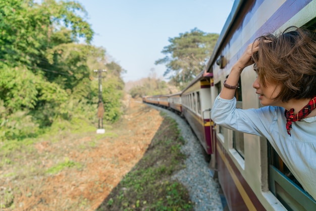 Feliz mujer mira desde la ventana viajando en tren en Tailandia