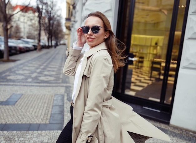 Feliz mujer de moda con gafas de sol cruzando la calle y mirando a la cámara