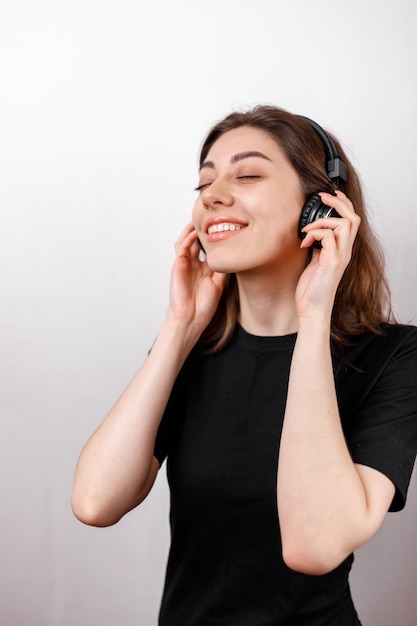 Feliz mujer morena sonriendo escuchando música con auriculares en un espacio en blanco aislado