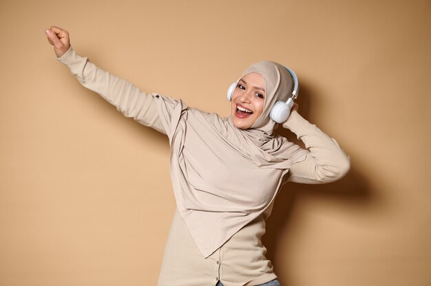 Feliz mujer musulmana con hijab, escuchando música en auriculares