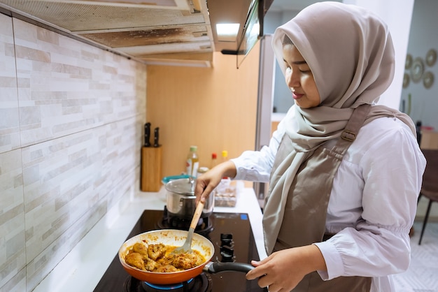 Feliz mujer musulmana preparando la cena iftar cocinando solo en la cocina