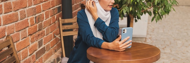 Feliz mujer musulmana con videollamada en smartphone en ciudad