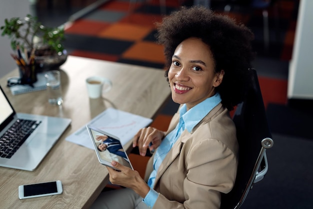 Feliz mujer de negocios afroamericana que tiene una conferencia telefónica sobre el panel táctil en la oficina