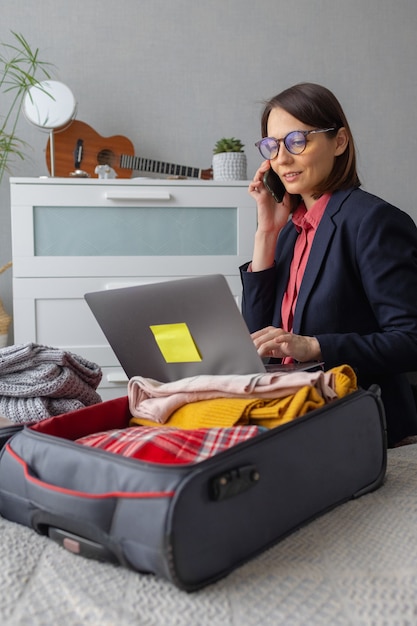 Una feliz mujer de negocios milenaria europea está empacando para la carretera empacando la maleta para una empresa