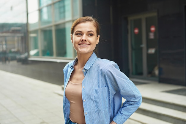 Feliz mujer de negocios segura de sí misma saliendo del moderno centro de oficinas