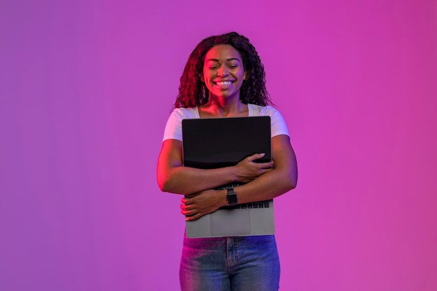 feliz, mujer negra, se abrazar, computadora de computadora portátil, con, pantalla en blanco, en, luz de neón