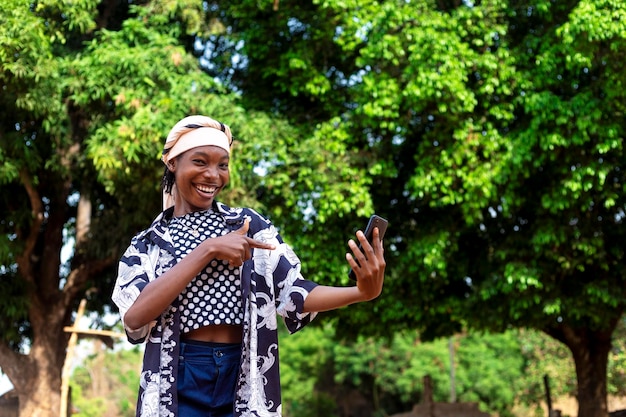 Feliz mujer negra africana con el teléfono apuntando