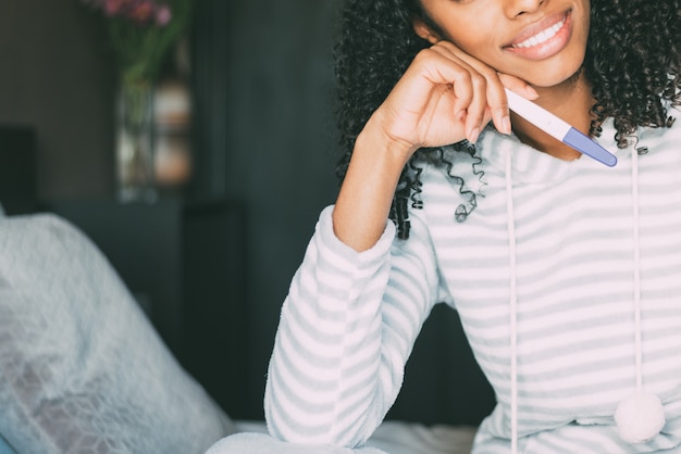 Feliz mujer negra con una prueba de embarazo en cama