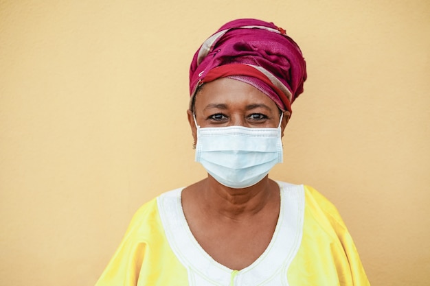 Feliz mujer negra senior con mascarilla con traje tradicional