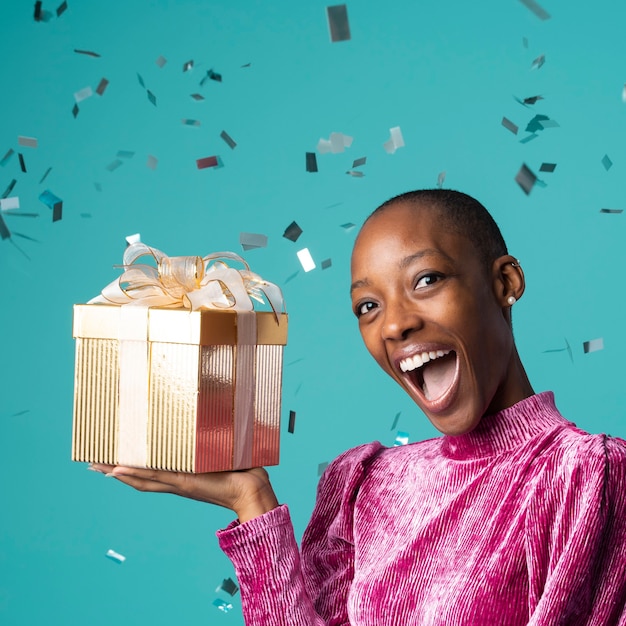 Feliz mujer negra sosteniendo una caja de regalo
