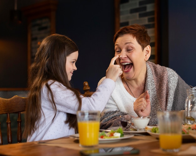 Foto feliz mujer y niña sentada en la mesa