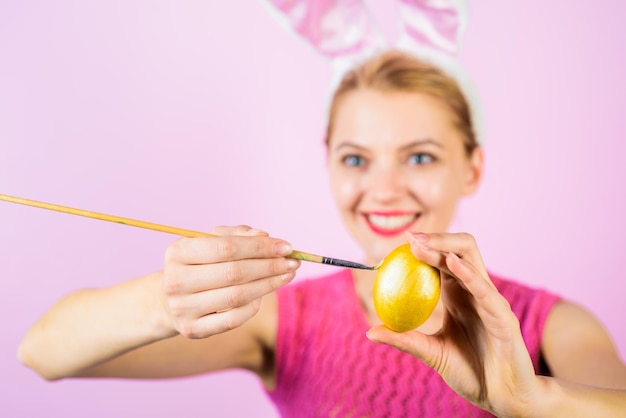 Feliz mujer de pascua con orejas de conejo pintando huevo concepto de pascua conejo blanco huevo de pascua ideas conejito