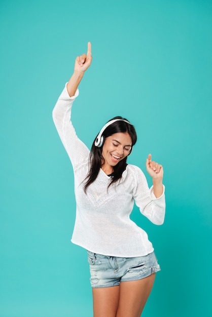 Feliz mujer relajada en auriculares bailando y escuchando música