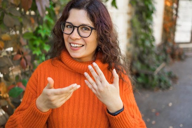 Feliz mujer rizada bloguera cara sonriente hablando con la cámara web grabando vlog Mujer influyente en las redes sociales transmitiendo haciendo videollamadas al aire libre Headshot retrato selfie cámara web vista