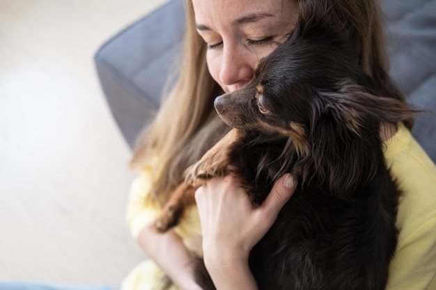 Feliz mujer rubia abrazo divertido terrier de juguete ruso marrón. Concepto de cuidado de mascotas. amor y amistad entre humanos y animales. Foto de alta calidad