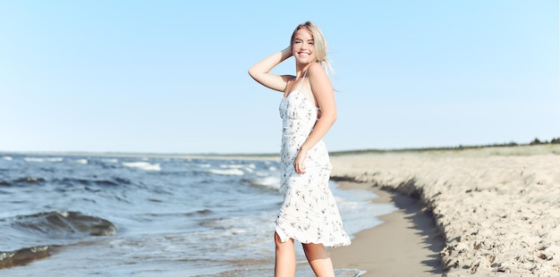 Feliz mujer rubia y hermosa divirtiéndose en la playa del océano mientras baila en las olas