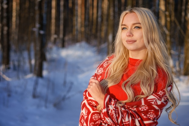 Feliz mujer rubia en suéter rojo en bosque de invierno