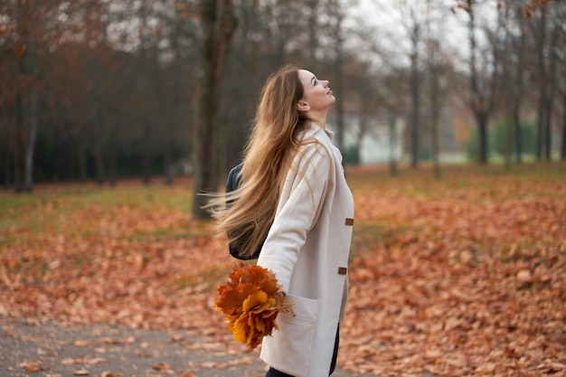 Feliz mujer rubia vestida con abrigo de otoño de moda y jeans negros