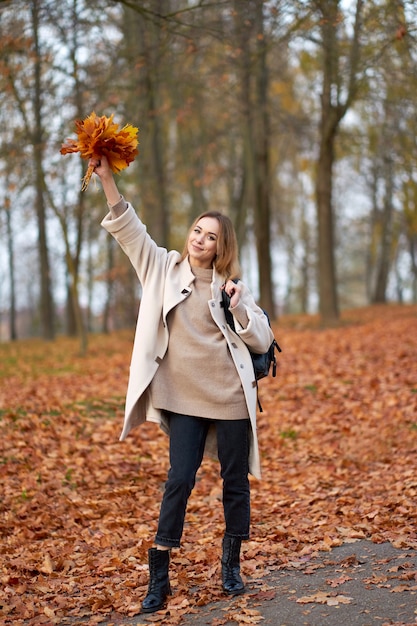 Feliz mujer rubia vestida con abrigo de otoño de moda y jeans negros