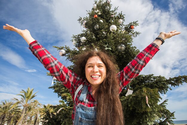 Foto feliz mujer saltando sobre fondo de árbol de navidad
