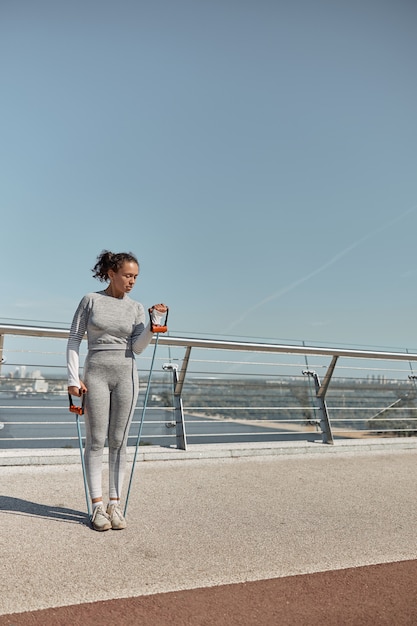 Feliz mujer sana y deportiva está haciendo ejercicios de arnés en un día soleado