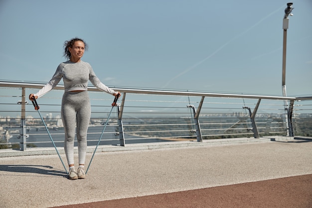 Feliz mujer sana y deportiva está haciendo ejercicios de arnés en un día soleado