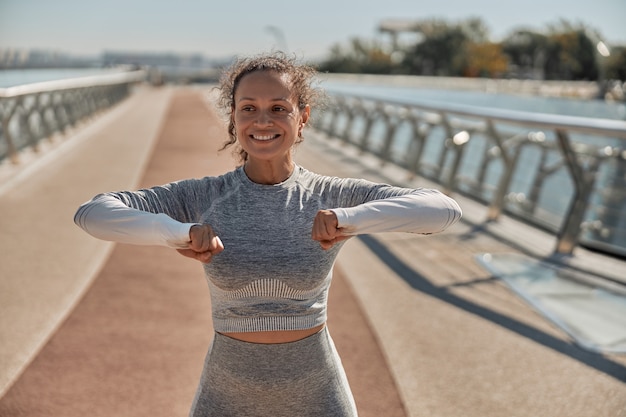 Feliz mujer sana y deportiva está haciendo entrenamientos de entrenamiento en un día soleado