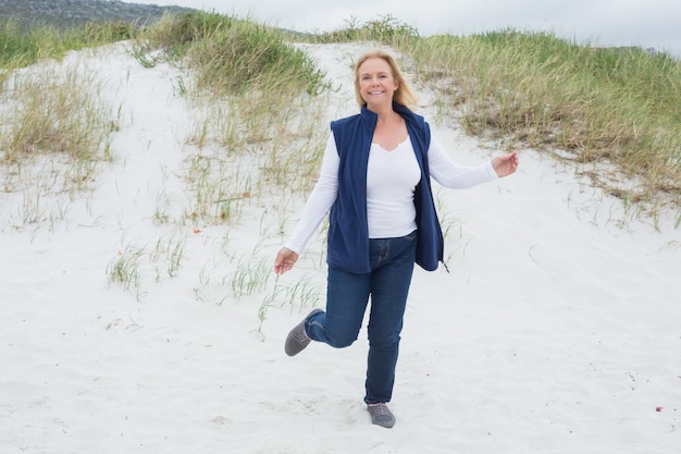 Feliz mujer senior corriendo en la playa