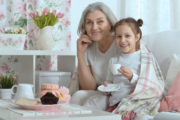 Feliz mujer senior con nieta con té en casa