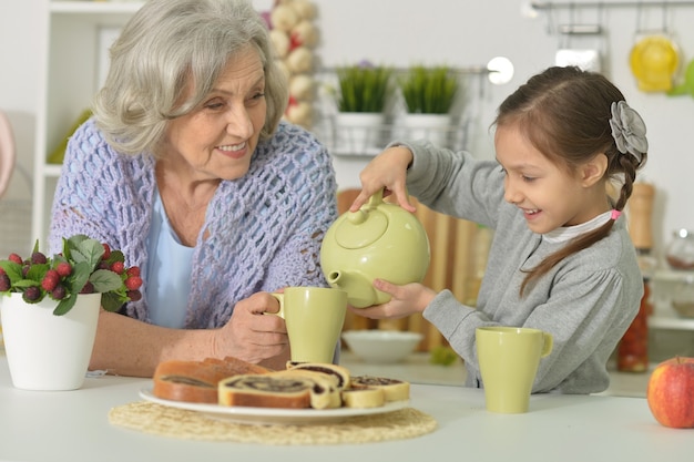 Feliz mujer senior con nieta con té en casa