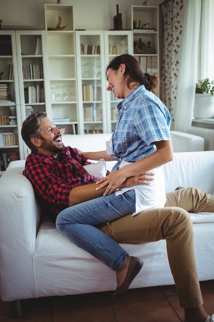 Feliz mujer sentada en la vuelta del hombre en la sala de estar